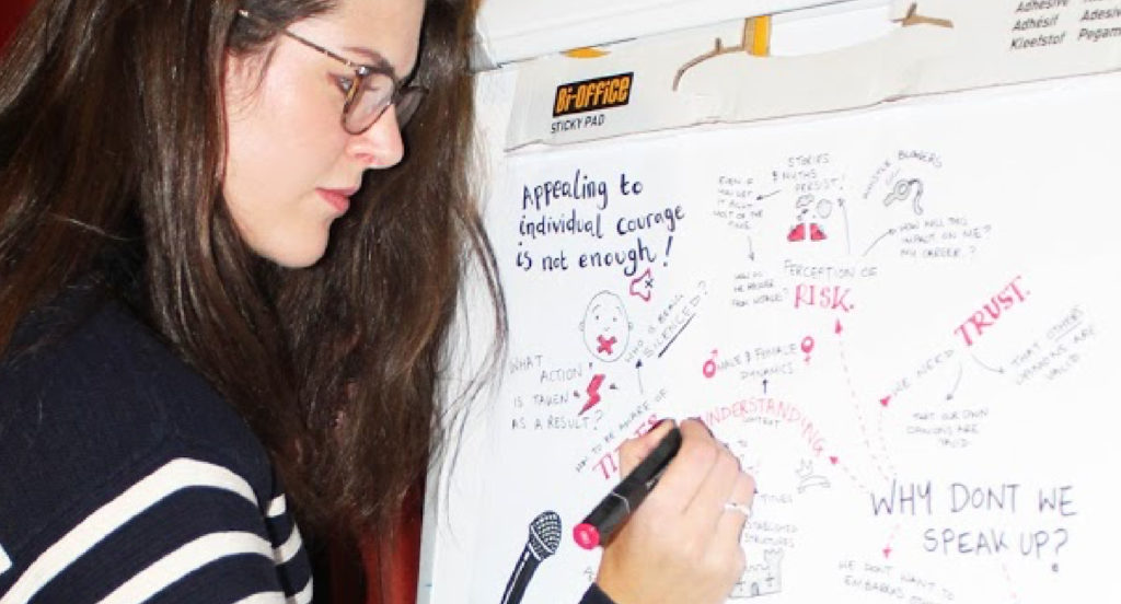 A woman writing sketch notes on a Stick Pad with a red pen
